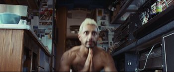 Movie still from “Sound of Metal” (2019), directed by Darius Marder – A man with a beard and a white hair is holding his hands together; Medium shot, Low angle