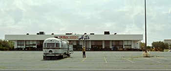A man standing in a parking lot next to an airstream trailer