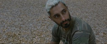 Movie still from “Sound of Metal” (2019), directed by Darius Marder – A man with white hair sitting on the ground looking at the camera; Close Up shot, High angle