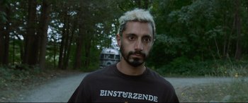Movie still from “Sound of Metal” (2019), directed by Darius Marder – A man with white hair stands in front of trees; Close Up shot, Over the shoulder angle