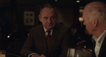 Movie still from “Spotlight” (2015), directed by Tom McCarthy – An older man wearing a suit and tie sitting at a table; Close Up shot, Over the shoulder angle
