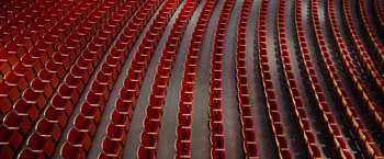 Movie still from “Steve Jobs” (2015), directed by Danny Boyle – Rows and rows of red seats in an auditorium; Extreme Wide shot, High angle