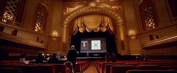 Movie still from “Steve Jobs” (2015), directed by Danny Boyle – People are sitting in a large auditorium watching a presentation; Extreme Wide shot, High angle