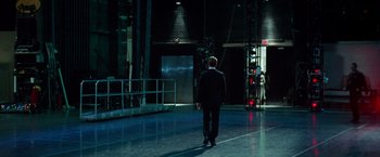 Movie still from “Steve Jobs” (2015), directed by Danny Boyle – A man in a black suit is standing in a dark room; Wide shot, Low angle