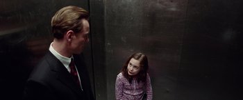 Movie still from “Steve Jobs” (2015), directed by Danny Boyle – A man and a young girl standing next to each other in front of a wall; Medium shot, Over the shoulder angle