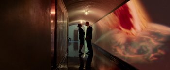 Movie still from “Steve Jobs” (2015), directed by Danny Boyle – A man and a woman standing next to each other in a hallway; Wide shot, Low angle