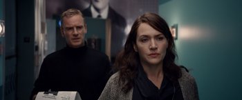 Movie still from “Steve Jobs” (2015), directed by Danny Boyle – A man and a woman standing next to each other in a room; Close Up shot, Over the shoulder angle