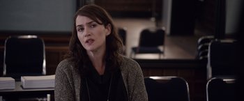 Movie still from “Steve Jobs” (2015), directed by Danny Boyle – A woman with long brown hair wearing a black shirt; Close Up shot, Over the shoulder angle