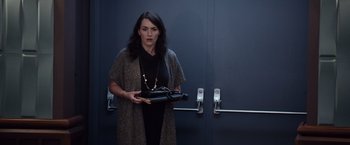 Movie still from “Steve Jobs” (2015), directed by Danny Boyle – A woman holding a purse in front of a door; Medium shot, Low angle