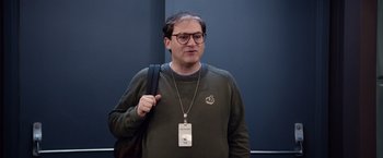 Movie still from “Steve Jobs” (2015), directed by Danny Boyle – A man wearing glasses and a green sweater; Medium shot, Over the shoulder angle