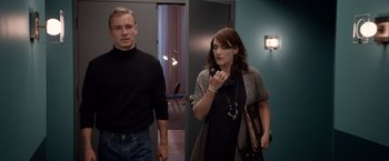 Movie still from “Steve Jobs” (2015), directed by Danny Boyle – A man and a woman standing next to each other in a room; Medium shot, Over the shoulder angle