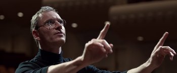 Movie still from “Steve Jobs” (2015), directed by Danny Boyle – An older man in a black shirt is holding his finger up; Close Up shot, Low angle