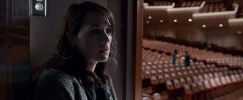 Movie still from “Steve Jobs” (2015), directed by Danny Boyle – A woman standing in front of an empty auditorium; Medium shot, Over the shoulder angle