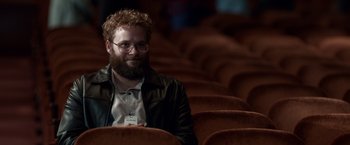 Movie still from “Steve Jobs” (2015), directed by Danny Boyle – A man with a beard sitting in an auditorium; Medium shot, Over the shoulder angle