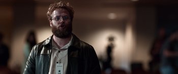 Movie still from “Steve Jobs” (2015), directed by Danny Boyle – A man with a beard wearing glasses and a leather jacket; Close Up shot, Over the shoulder angle