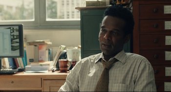 Movie still from “Stillwater” (2021), directed by Tom McCarthy – A man wearing a tie sitting in front of a desk; Close Up shot, Over the shoulder angle