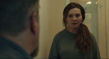 Movie still from “Stillwater” (2021), directed by Tom McCarthy – A woman standing in front of a mirror looking at herself in the mirror; Close Up shot, Over the shoulder angle