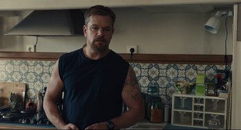 Movie still from “Stillwater” (2021), directed by Tom McCarthy – A man standing in a kitchen with his hands on his hips; Medium shot, Over the shoulder angle