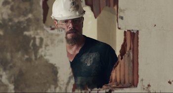 Movie still from “Stillwater” (2021), directed by Tom McCarthy – A man wearing a hard hat in a room with plaster on the wall; Medium shot, Over the shoulder angle