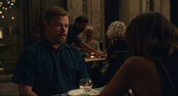 Movie still from “Stillwater” (2021), directed by Tom McCarthy – A man sitting at a table with a glass of white wine; Medium shot, Over the shoulder angle