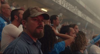 Movie still from “Stillwater” (2021), directed by Tom McCarthy – A man with a beard and a baseball cap is in the stands; Close Up shot, Low angle