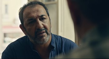 Movie still from “Stillwater” (2021), directed by Tom McCarthy – A person sitting in a room; Close Up shot, Over the shoulder angle