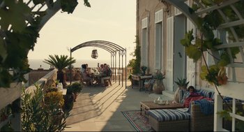 Movie still from “Stillwater” (2021), directed by Tom McCarthy – A group of people sitting at a table on a patio; Extreme Wide shot, High angle
