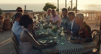 Movie still from “Stillwater” (2021), directed by Tom McCarthy – A group of people sitting at a table with plates of food on it; Wide shot, Over the shoulder angle