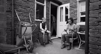 Movie still from “Belfast” (2021), directed by Kenneth Branagh – A couple of people that are sitting on some chairs; Wide shot, High angle