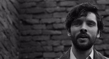 Movie still from “Belfast” (2021), directed by Kenneth Branagh – Black and white photograph of a bearded man in front of a brick wall; Close Up shot, Over the shoulder angle
