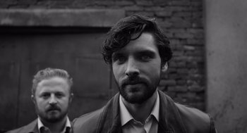 Movie still from “Belfast” (2021), directed by Kenneth Branagh – A black and white photo of a man with a beard; Close Up shot, Over the shoulder angle