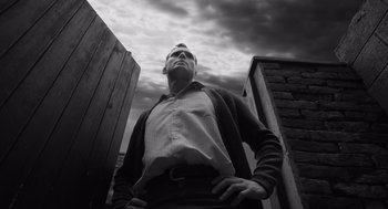 Movie still from “Belfast” (2021), directed by Kenneth Branagh – A black and white photo of a man looking up at the sky; Medium shot, Low angle