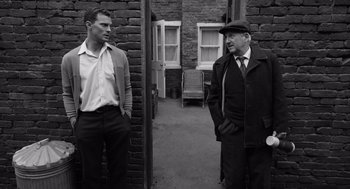 Movie still from “Belfast” (2021), directed by Kenneth Branagh – Two men standing next to each other on a sidewalk; Medium shot, Over the shoulder angle