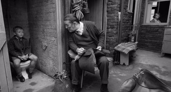 Movie still from “Belfast” (2021), directed by Kenneth Branagh – An older man sitting on a chair outside; Medium shot, High angle