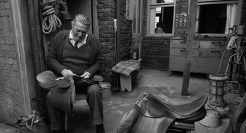 Movie still from “Belfast” (2021), directed by Kenneth Branagh – An older man sitting in a chair in a room; Medium shot, High angle