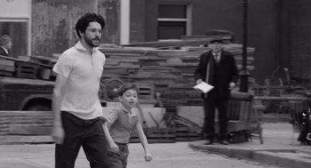 Movie still from “Belfast” (2021), directed by Kenneth Branagh – A man and a boy are playing with a frisbee; Medium shot, Over the shoulder angle