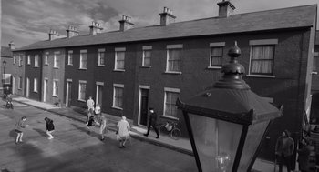 Movie still from “Belfast” (2021), directed by Kenneth Branagh – A black and white photo of people walking down a street; Extreme Wide shot, High angle