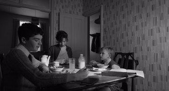 Movie still from “Belfast” (2021), directed by Kenneth Branagh – A group of people sitting around a table eating; Medium shot, High angle