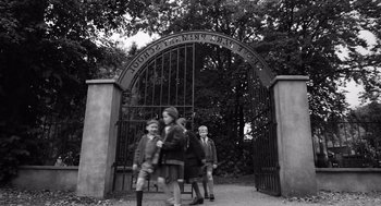 Movie still from “Belfast” (2021), directed by Kenneth Branagh – Three children are standing in front of an iron gate; Wide shot, High angle