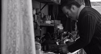 Movie still from “Belfast” (2021), directed by Kenneth Branagh – A man working in a shop with many tools on the table; Medium shot, Low angle