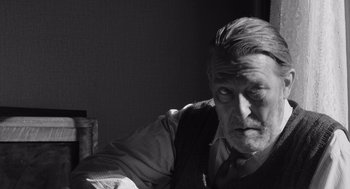 Movie still from “Belfast” (2021), directed by Kenneth Branagh – An older man sitting at a table in a dark room; Close Up shot, Low angle