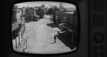 Movie still from “Belfast” (2021), directed by Kenneth Branagh – A black and white photo of a person walking on a dirt road; Extreme Wide shot, High angle