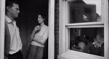 Movie still from “Belfast” (2021), directed by Kenneth Branagh – A black and white photo of a woman standing in front of an open window; Medium shot, Low angle