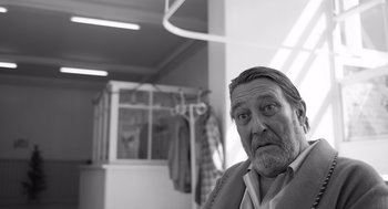 Movie still from “Belfast” (2021), directed by Kenneth Branagh – An older man with a beard is looking at the camera; Close Up shot, Over the shoulder angle