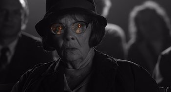 Movie still from “Belfast” (2021), directed by Kenneth Branagh – An older woman wearing a hat and glasses; Close Up shot, Over the shoulder angle