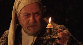Movie still from “Belfast” (2021), directed by Kenneth Branagh – An old man holding a lit candle in a dark room; Close Up shot, Low angle