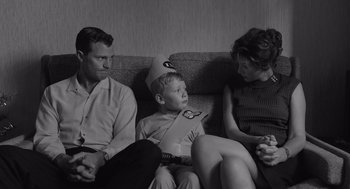 Movie still from “Belfast” (2021), directed by Kenneth Branagh – A man and a woman sitting next to a young boy; Medium shot, High angle