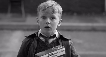 Movie still from “Belfast” (2021), directed by Kenneth Branagh – A young boy holding a pack of cigarettes; Medium shot, Low angle