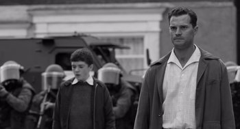 Movie still from “Belfast” (2021), directed by Kenneth Branagh – A black and white photo of a man and two boys; Medium shot, Over the shoulder angle