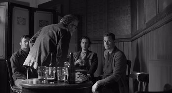 Movie still from “Belfast” (2021), directed by Kenneth Branagh – A group of men sitting at a table with drinks; Medium shot, Over the shoulder angle